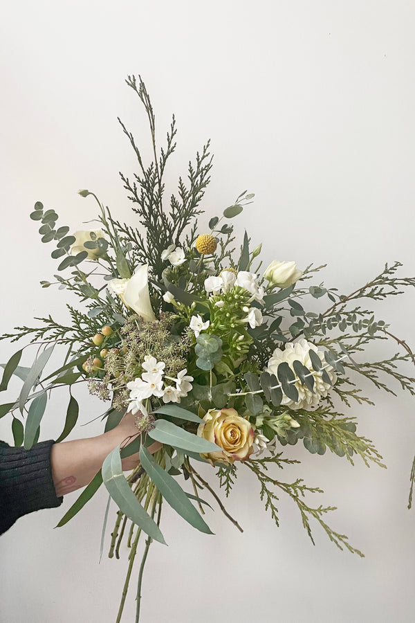 A hand holds an example of fresh Floral Arrangement Eggnog for $60 by Sprout Home Floral in Chicago