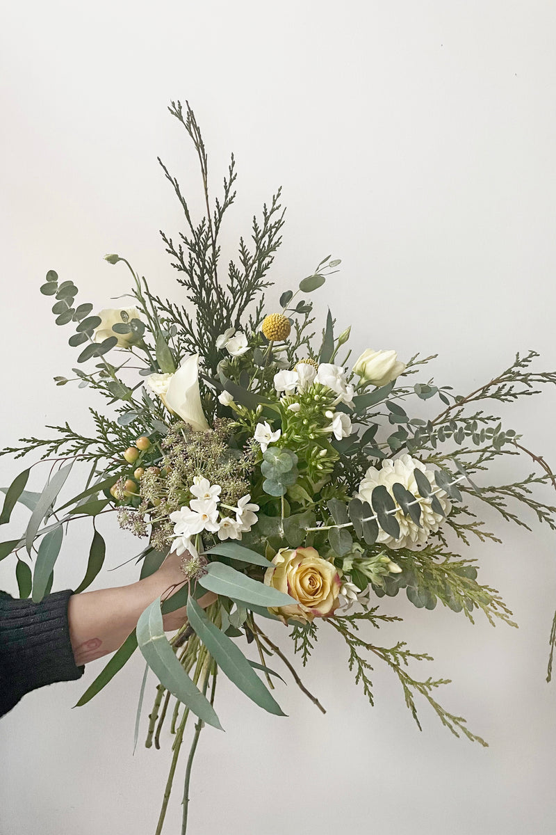 A hand holds an example of fresh Floral Arrangement Eggnog for $60 by Sprout Home Floral in Chicago