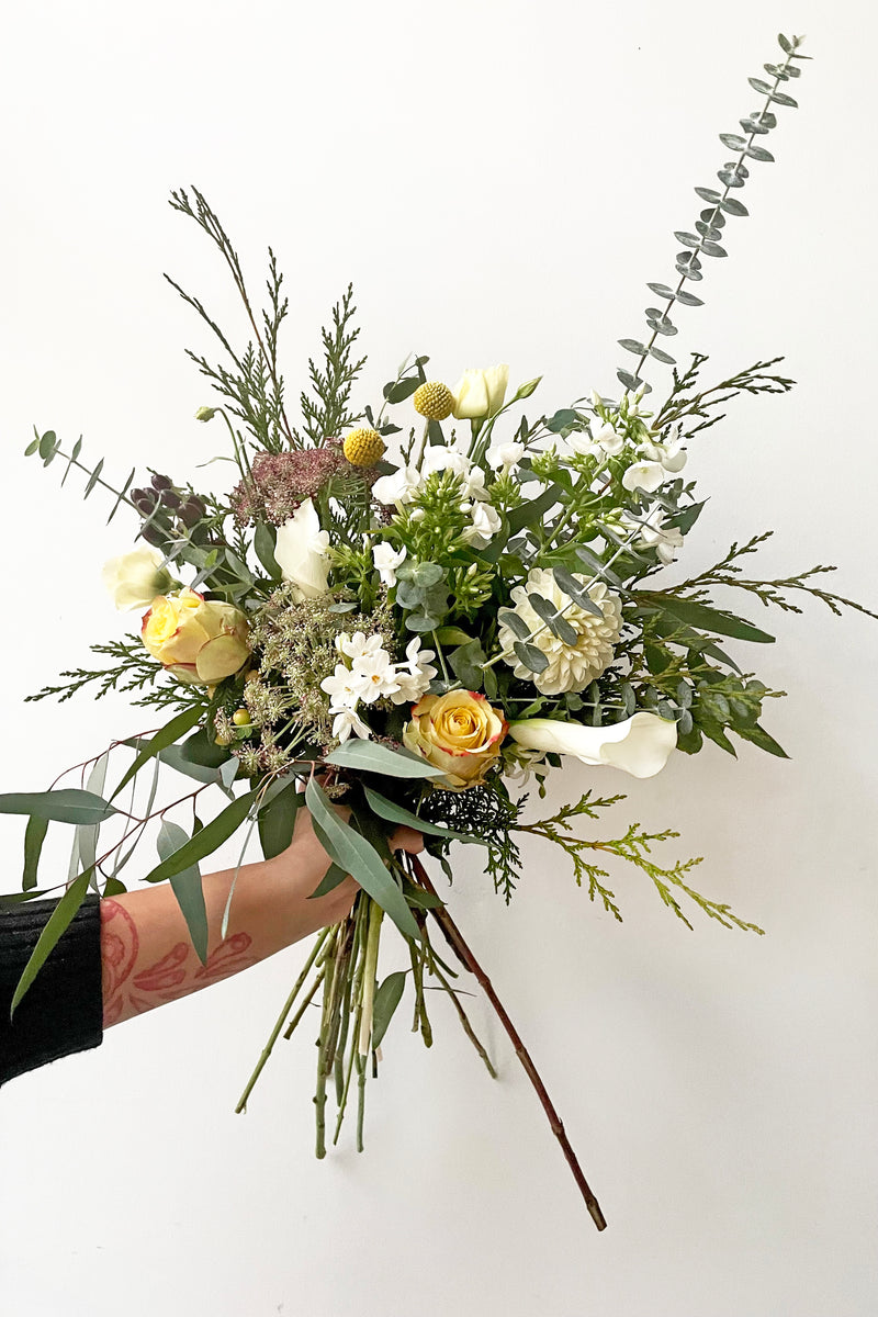 A hand holds fresh Floral Arrangement Eggnog for $85 from Sprout Home Floral in Chicago