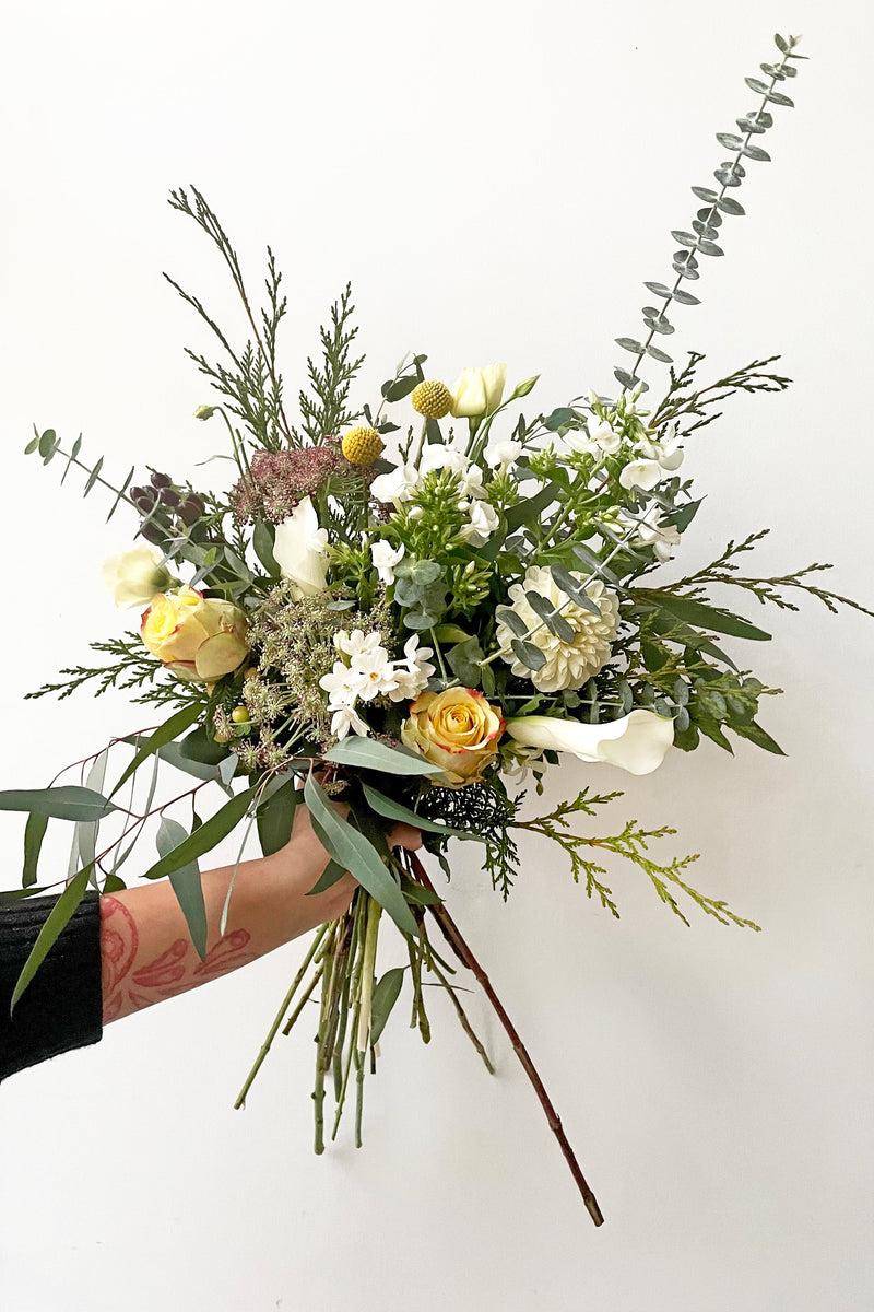 A hand holds fresh Floral Arrangement Champagne Toast for $85 from Sprout Home Floral in Chicago