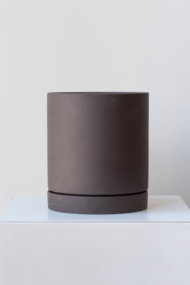Charcoal medium Sekki plant pot by Ferm Living on a white pedestal in front of a white background