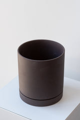 Charcoal medium Sekki plant pot by Ferm Living on a white pedestal in front of a white background
