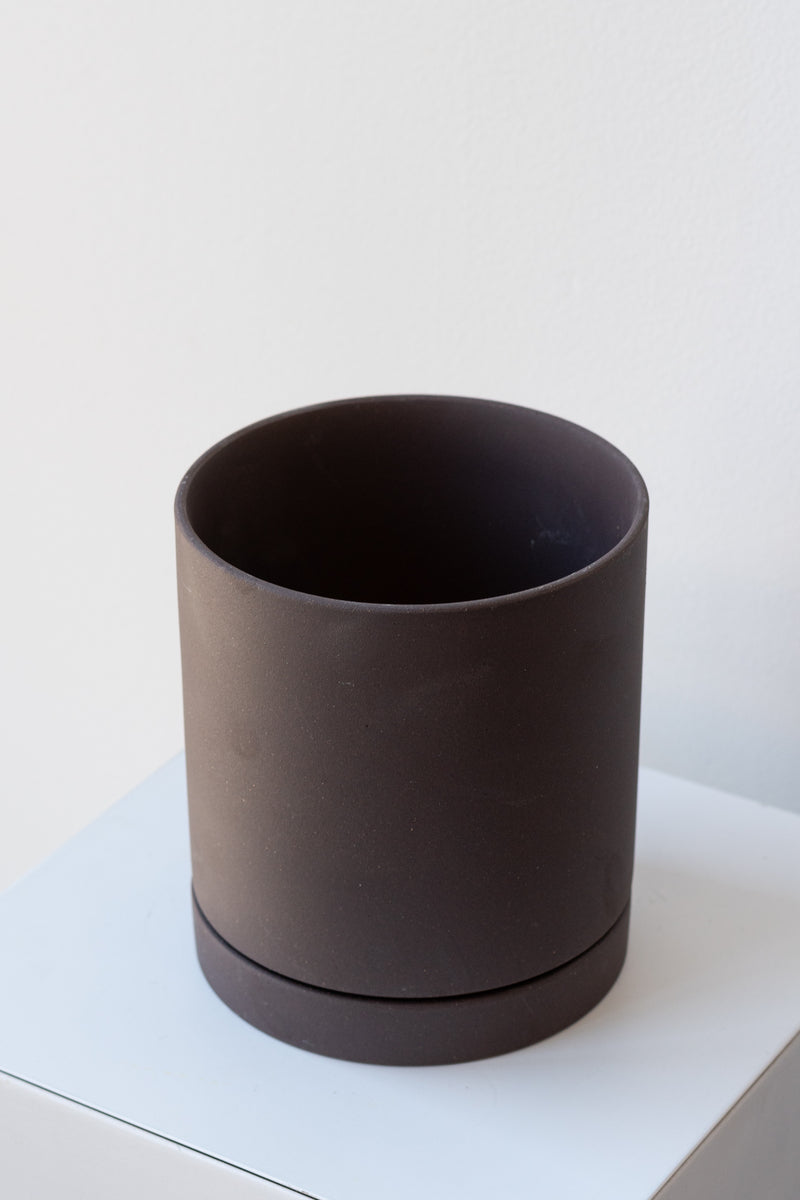 Charcoal medium Sekki plant pot by Ferm Living on a white pedestal in front of a white background