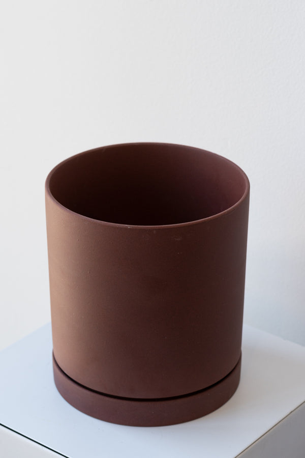 Rust large Sekki plant pot by Ferm Living on a white pedestal in front of a white background