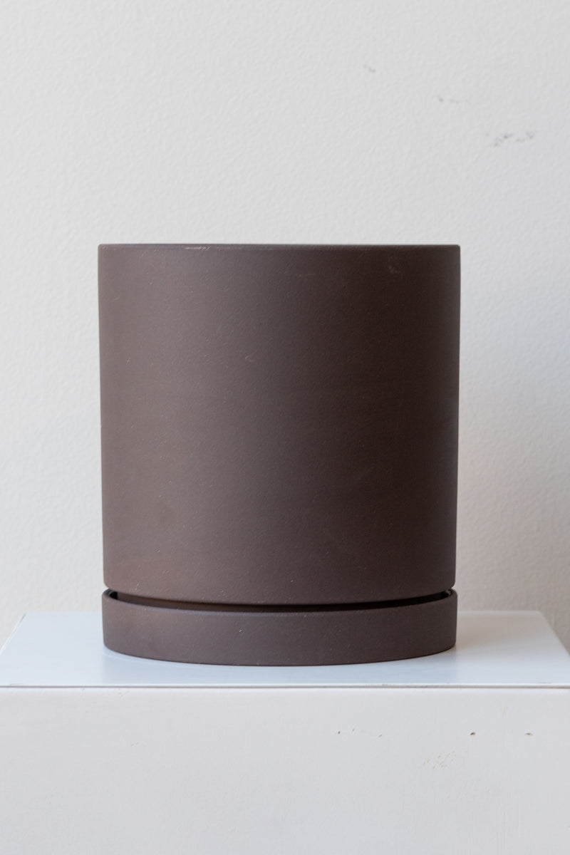 Charcoal large Sekki plant pot by Ferm Living on a white pedestal in front of a white background