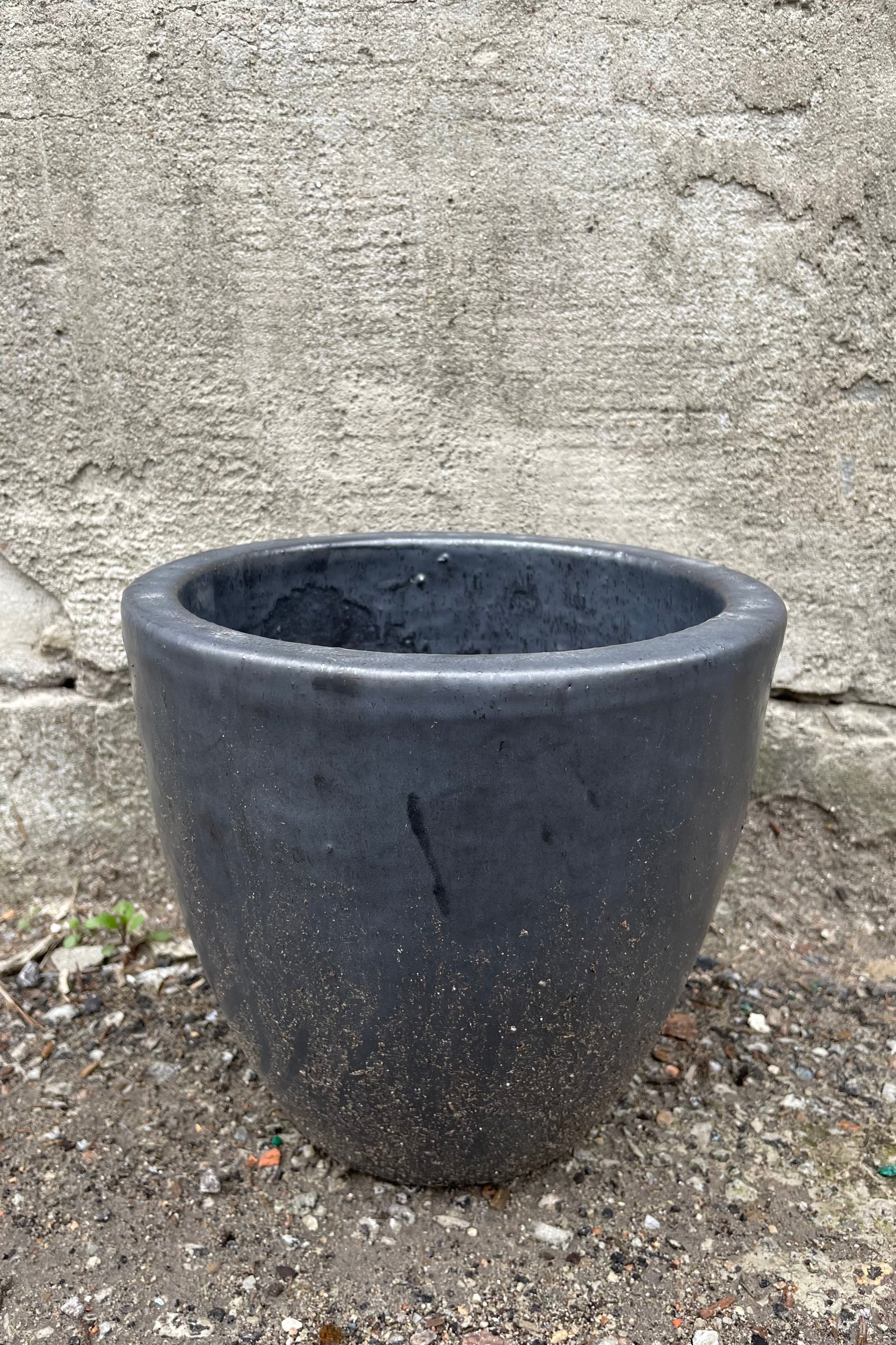 Egg Ceramic Planter Graphite Small against a grey wall ©Sprout Home
