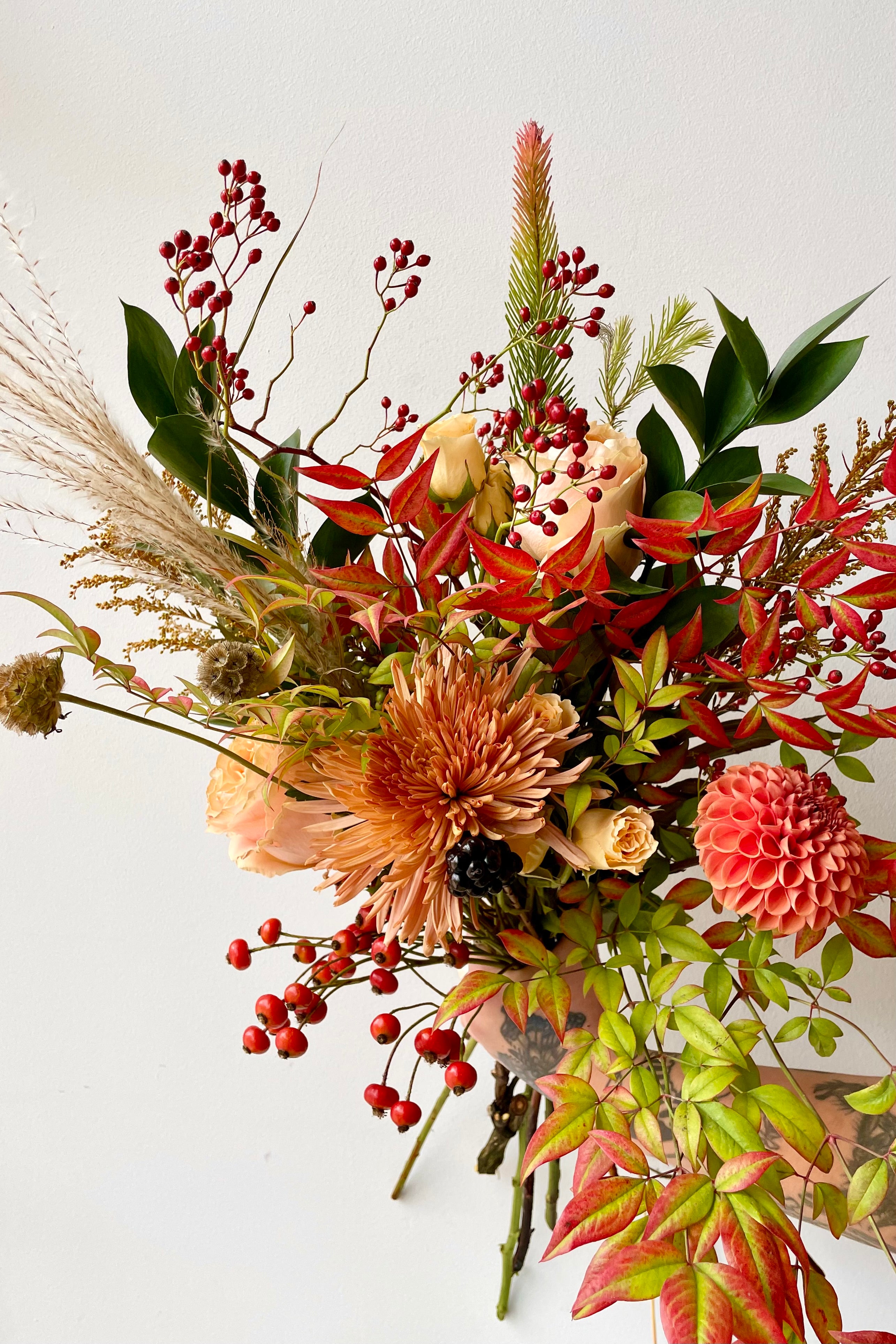 Floral arrangement 'Harvest Moon' by Sprout Home being held against a white wall. #size_$65