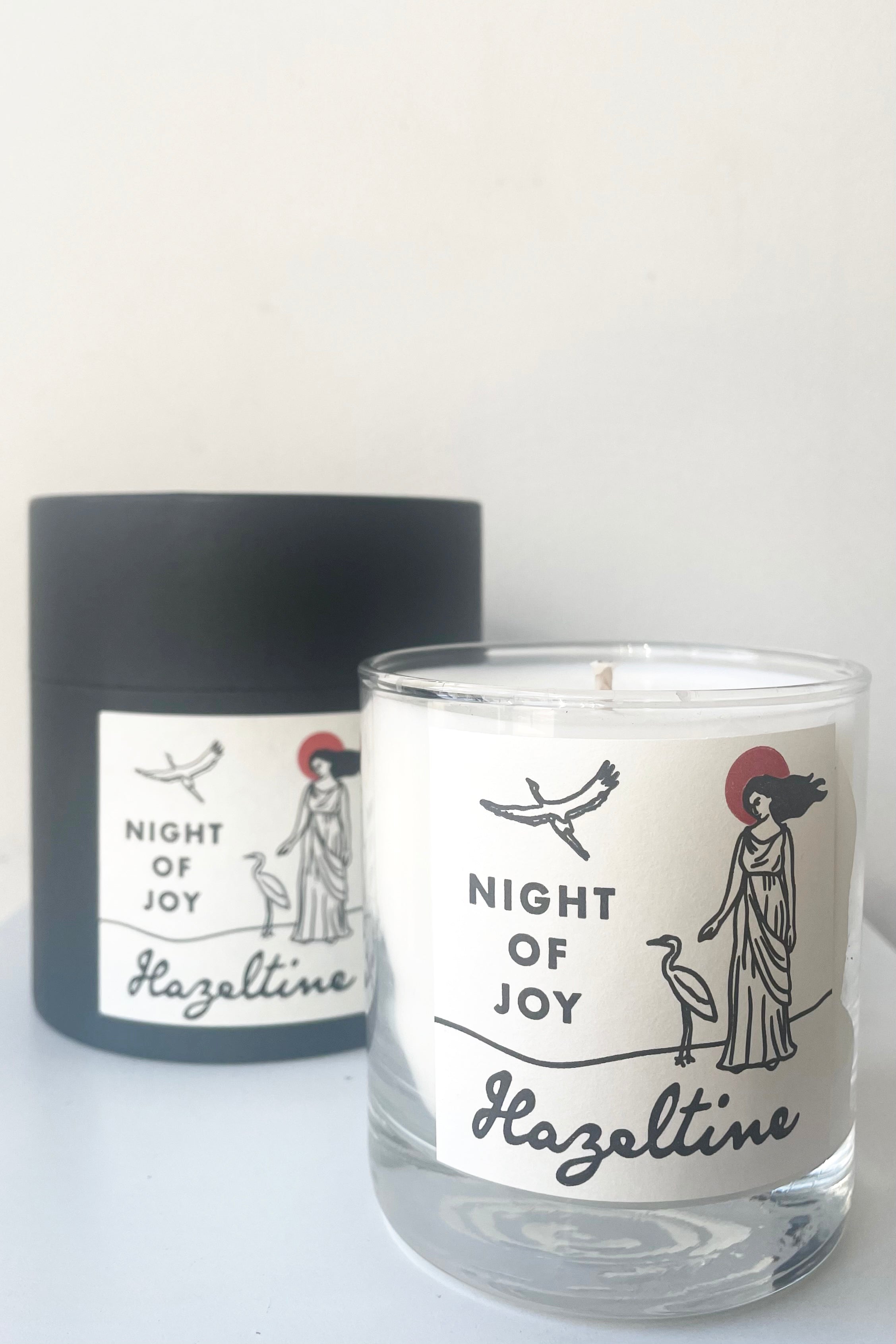 A view of candle and packaging of Hazeltine Candle night of joy against white backdrop