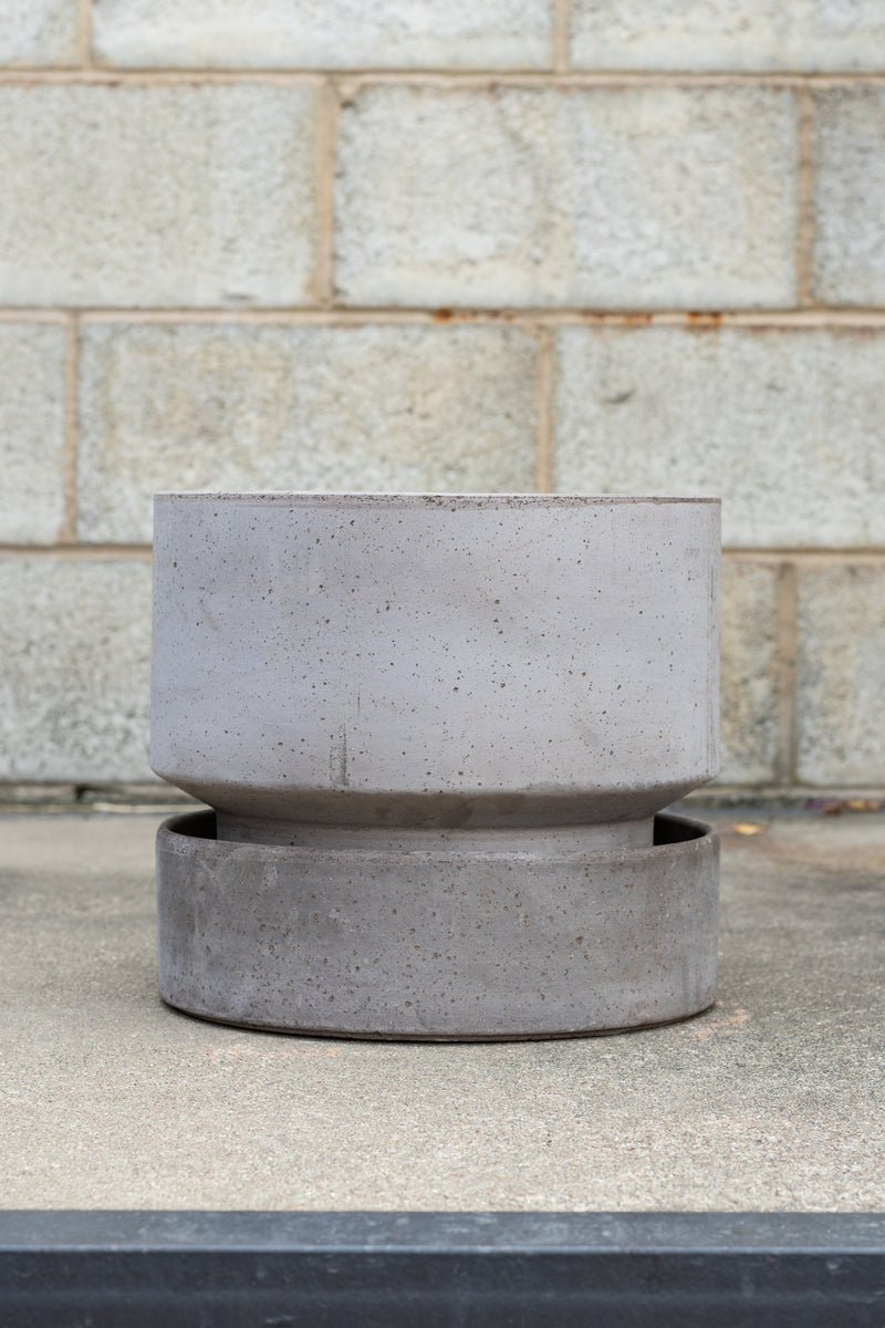 Bergs Potter Hoff Pot & Saucer grey 11.8” in front of concrete brick wall