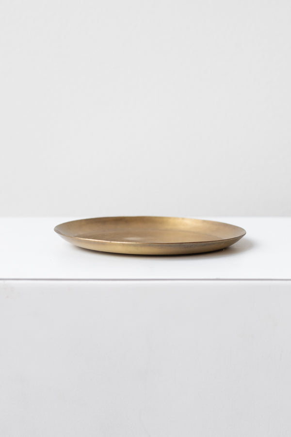 Fog Linen Work medium brass round plate on a white surface in a white room
