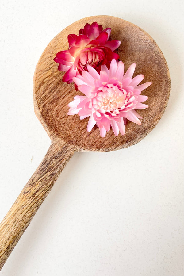 detail of Mango Wood Spoon, 24cm with two pink dried flowers against a white background