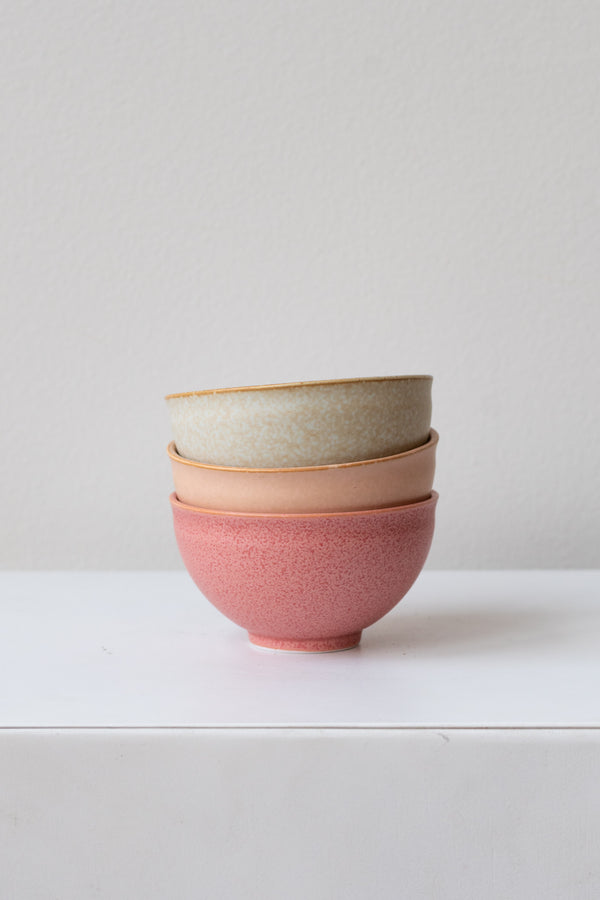 Stacked from top to bottom: grey, orange, and hot pink Ishi teacups by Miya Company Inc on a white surface in a white room