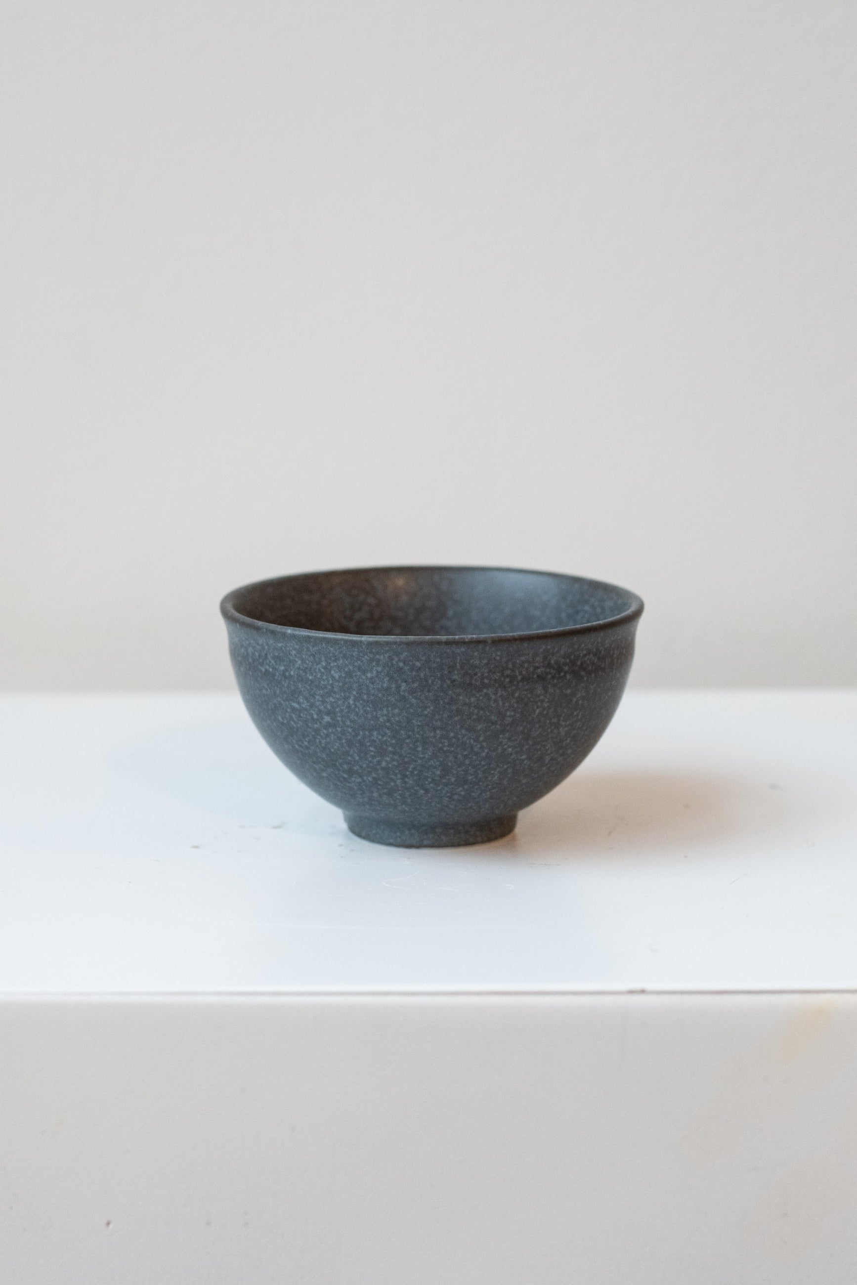 A traditional Japanese black teacup with a speckled matte glaze, displayed on a white surface. ©Sprout Home