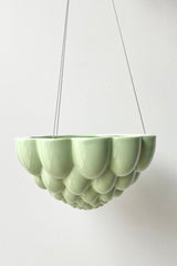 Green Jelly hanging planter against a white wall. 