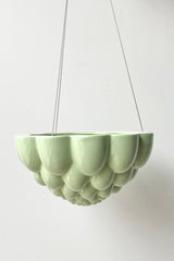 Green Jelly hanging planter against a white wall. 