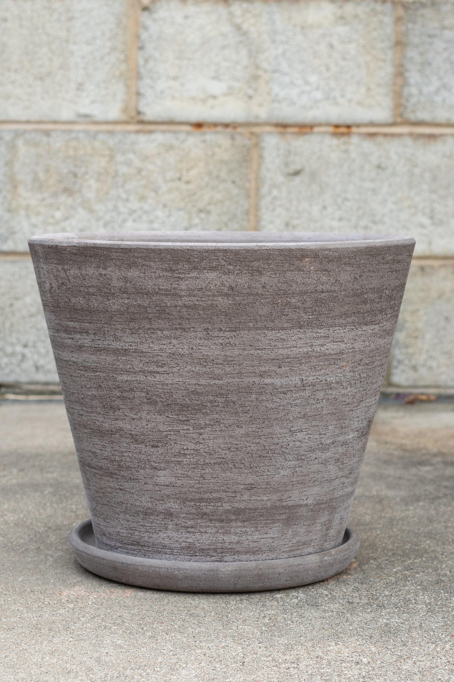 Bergs Potter Julie Pot & Saucer grey 13.8” in front of concrete brick wall