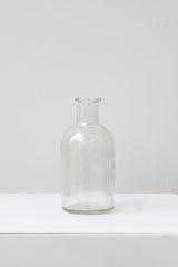 Clear medicine glass bud vase in front of white background