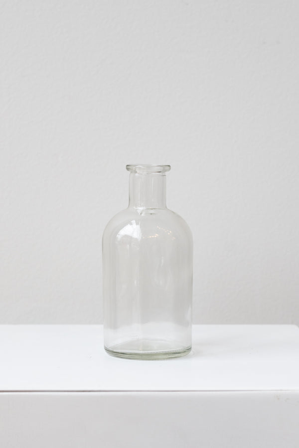 Clear medicine glass bud vase in front of white background
