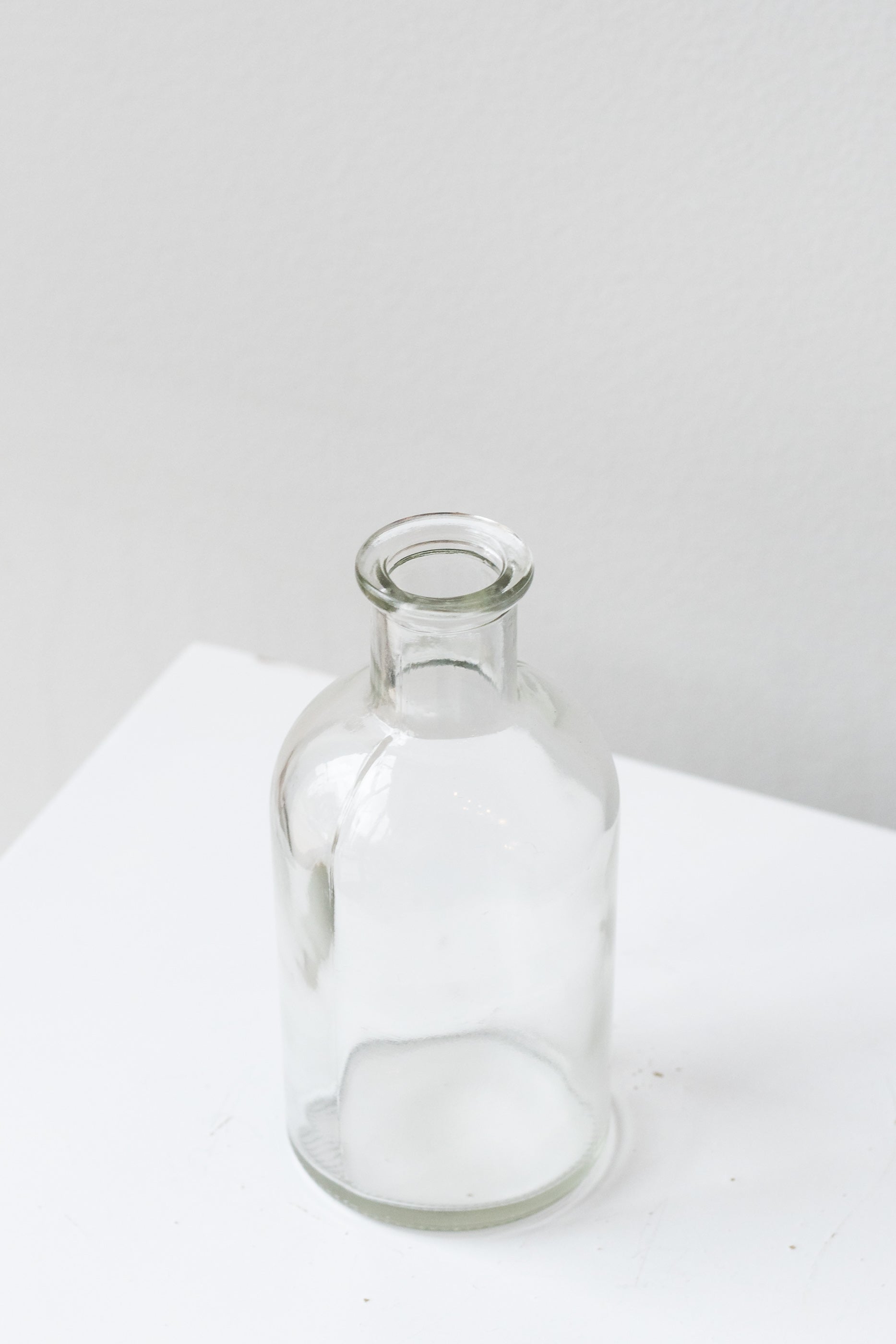 Clear medicine glass bud vase in front of white background