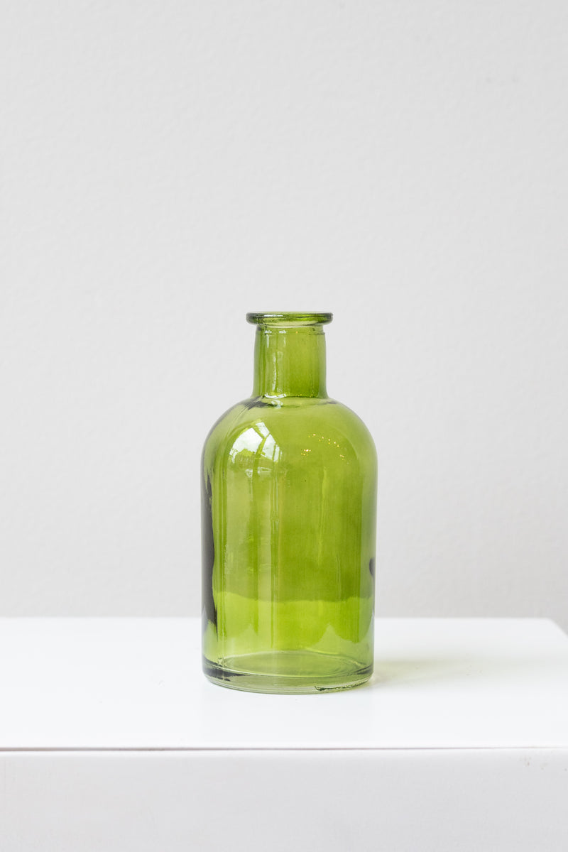 Green medicine glass bud vase in front of white background