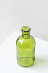 Green medicine glass bud vase in front of white background