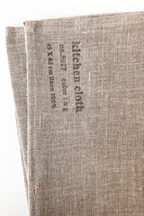 Detail of the Fog Linen natural linen kitchen cloth held in front of white background