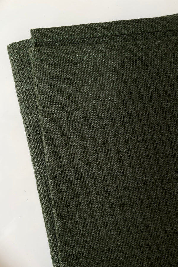 detail of Fog Linen laurel dark green kitchen cloth held in front of white background