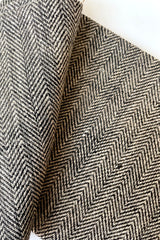 A detailed view of the Kitchen Cloth linen black herringbone napkin against a white background