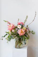 Large pastel Dawn floral arrangement by Sprout Home sits on a white pedestal in front of a white wall