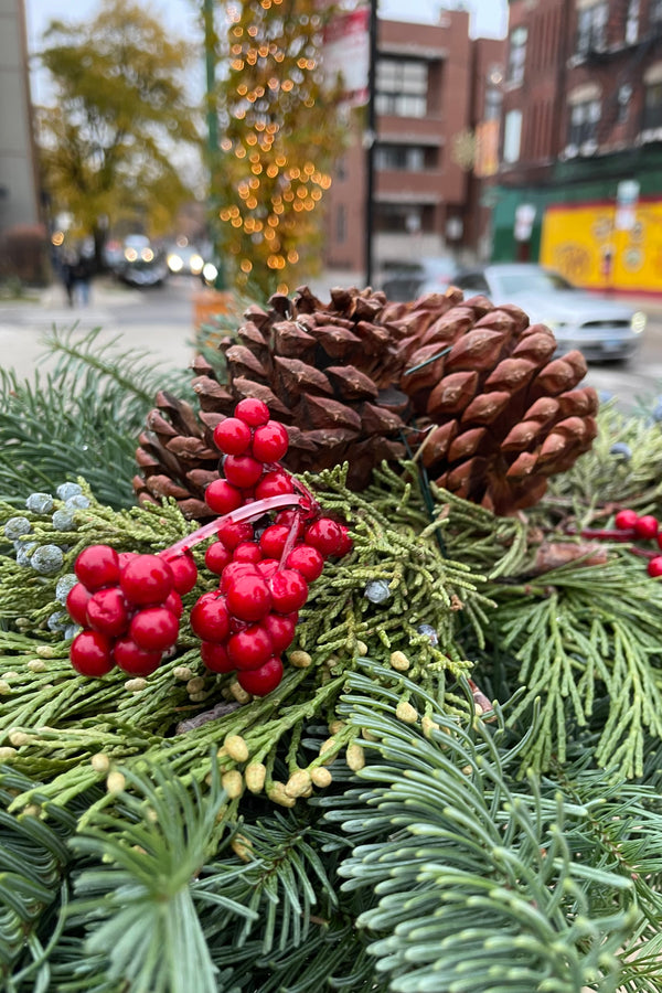 Top middle detail of an evergreen swag with faux canella berries and pine cones. 