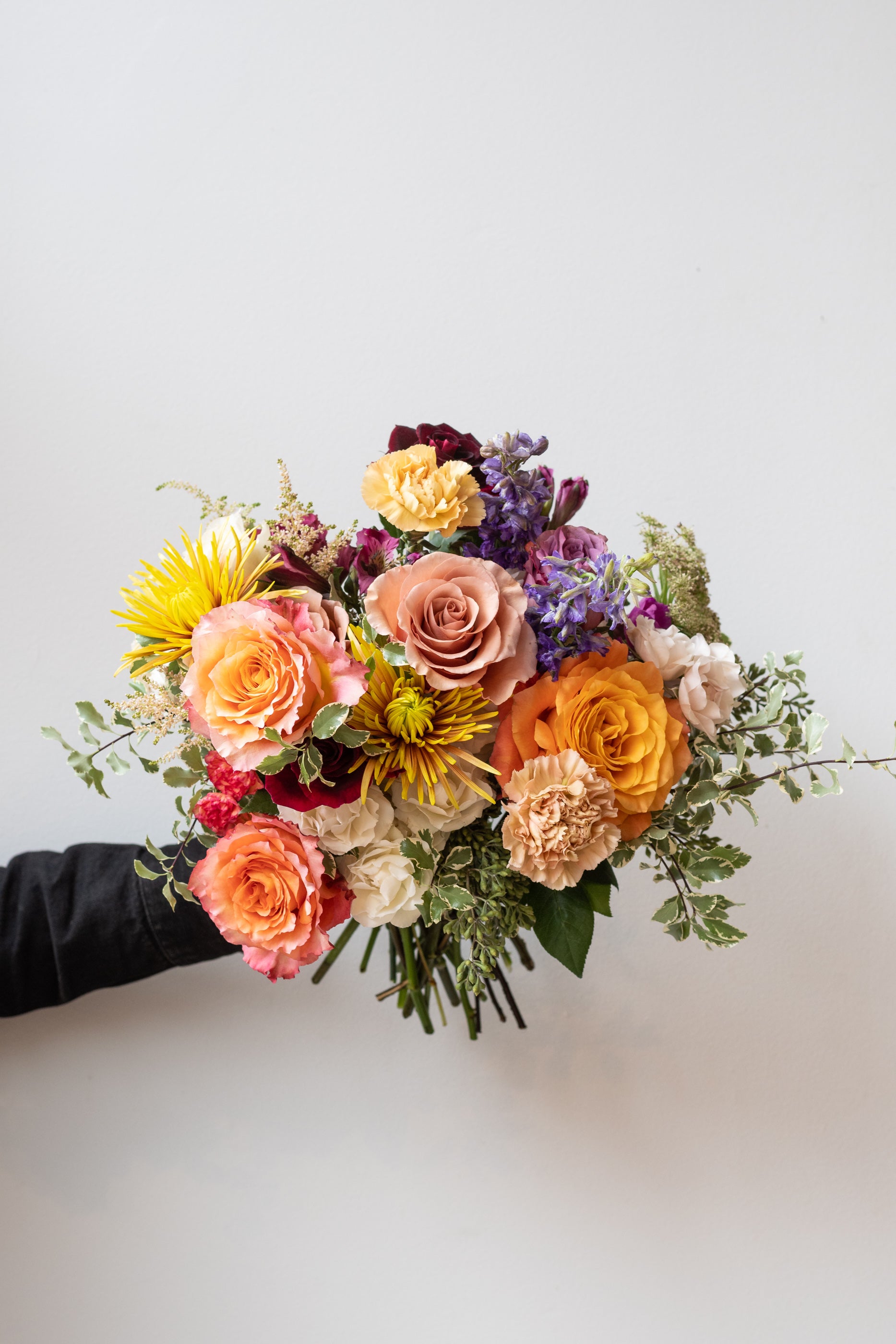 Handheld Midday floral arrangement in front of white background #size_$125