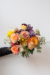 Handheld Midday floral arrangement in front of white background