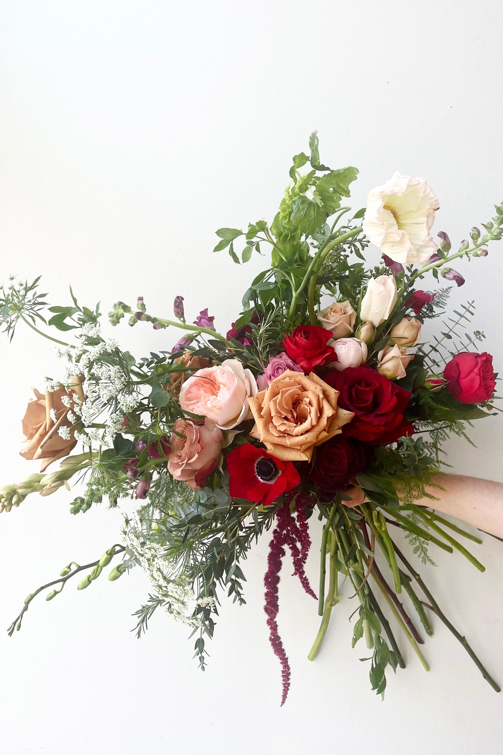 A hand holds an example of fresh Floral Arrangement Modern Love $125 from Sprout Home Floral in Chicago for Valentine's Day #size_$130