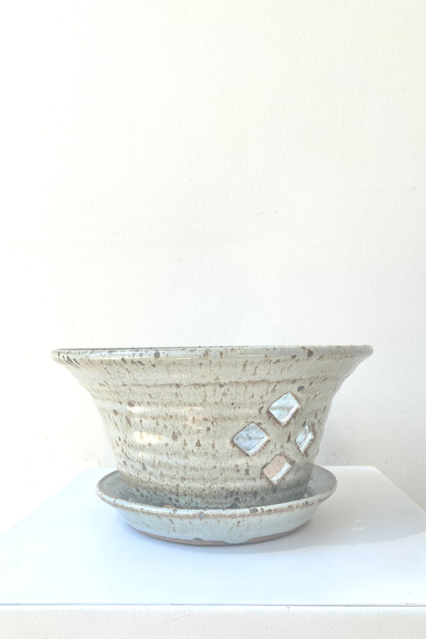 A full-body view of the 5" cornflower orchid pot and attached saucer with a view of 4 of the diamond-shaped side drainage holes