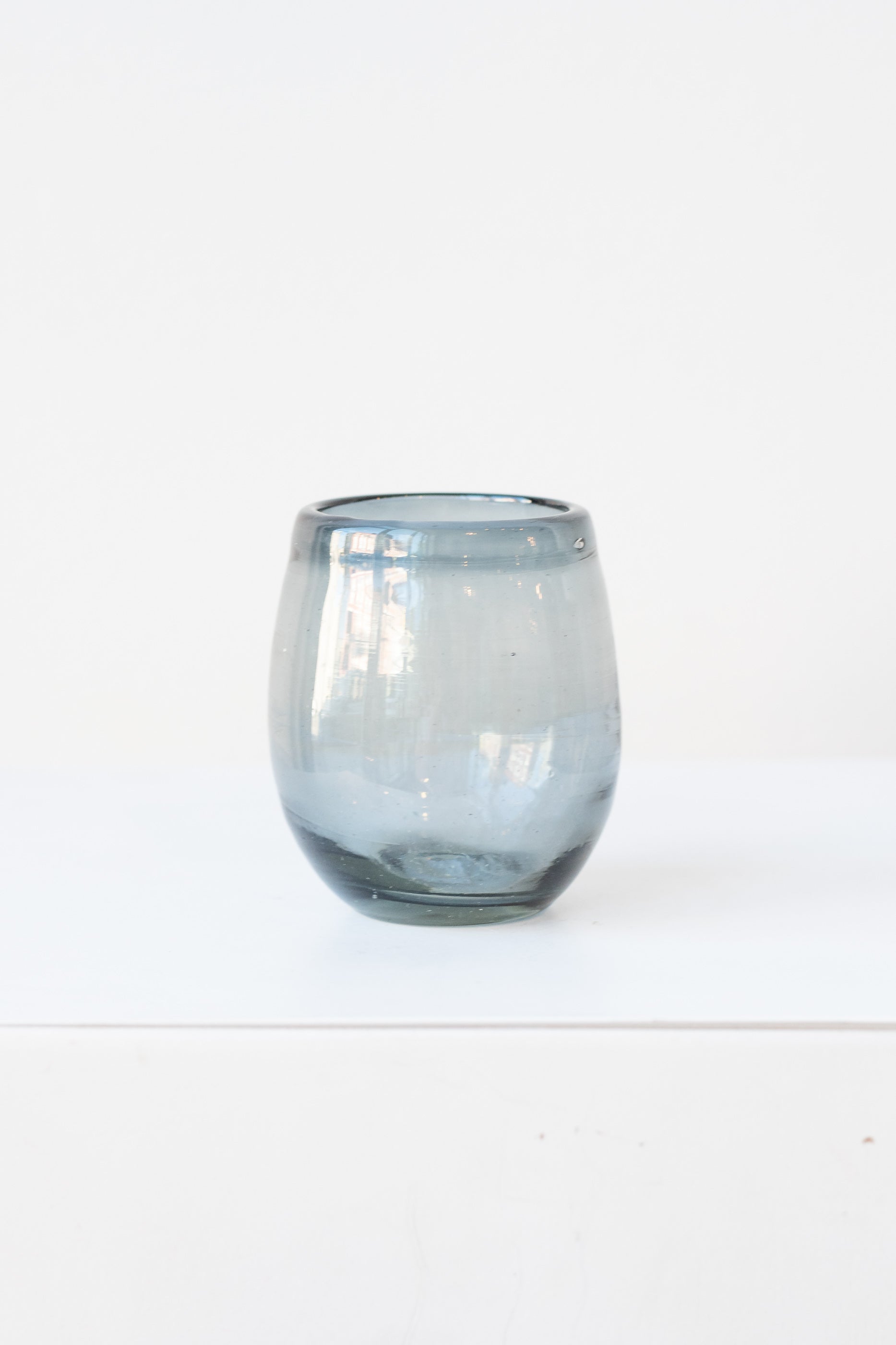 Small smoke oval colored wine glass on a white table in a white room