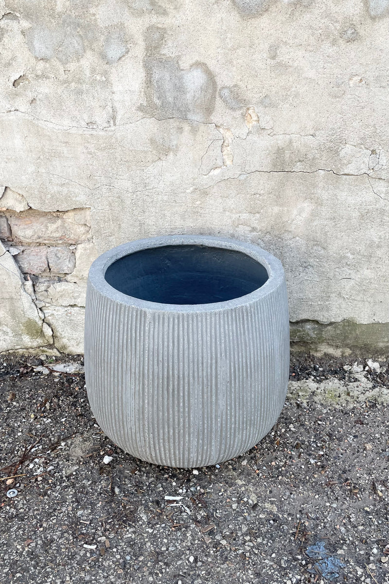 The dark grey medium pax pot with ridges against a concrete wall at Sprout Home.