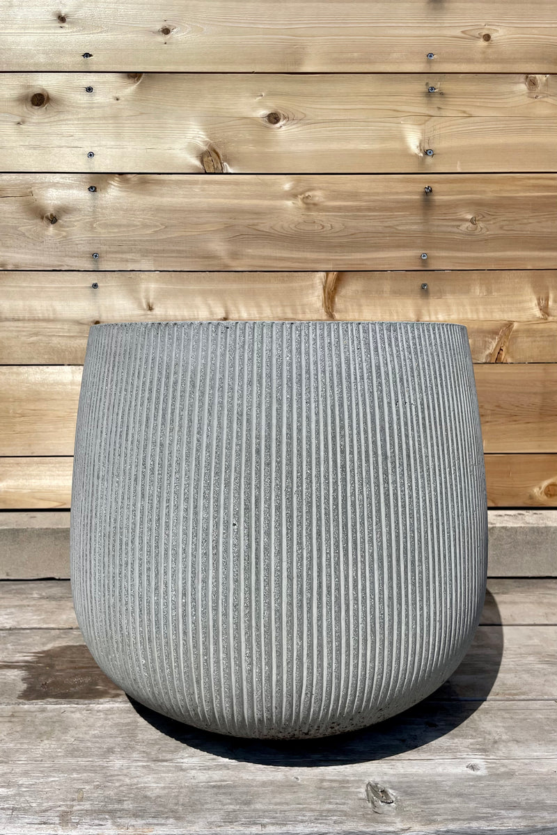 Pax Pot Vertical Ridged Light Grey Large against a wooden fence