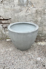 Detail of top of Jesslyn Pot vertical ridged light grey extra small against a grey wall