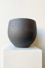 Mini Orb Pot Black Washed Large against a white wall