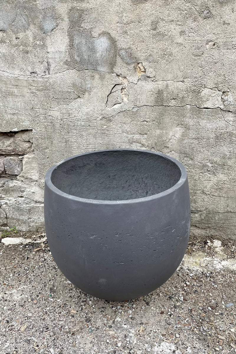 Detail of the top of the Mini Orb Pot Black Washed Extra Large against a grey wall 