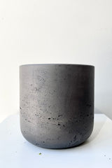 The black washed extra small Charlie pot against a white wall at Sprout Home. 