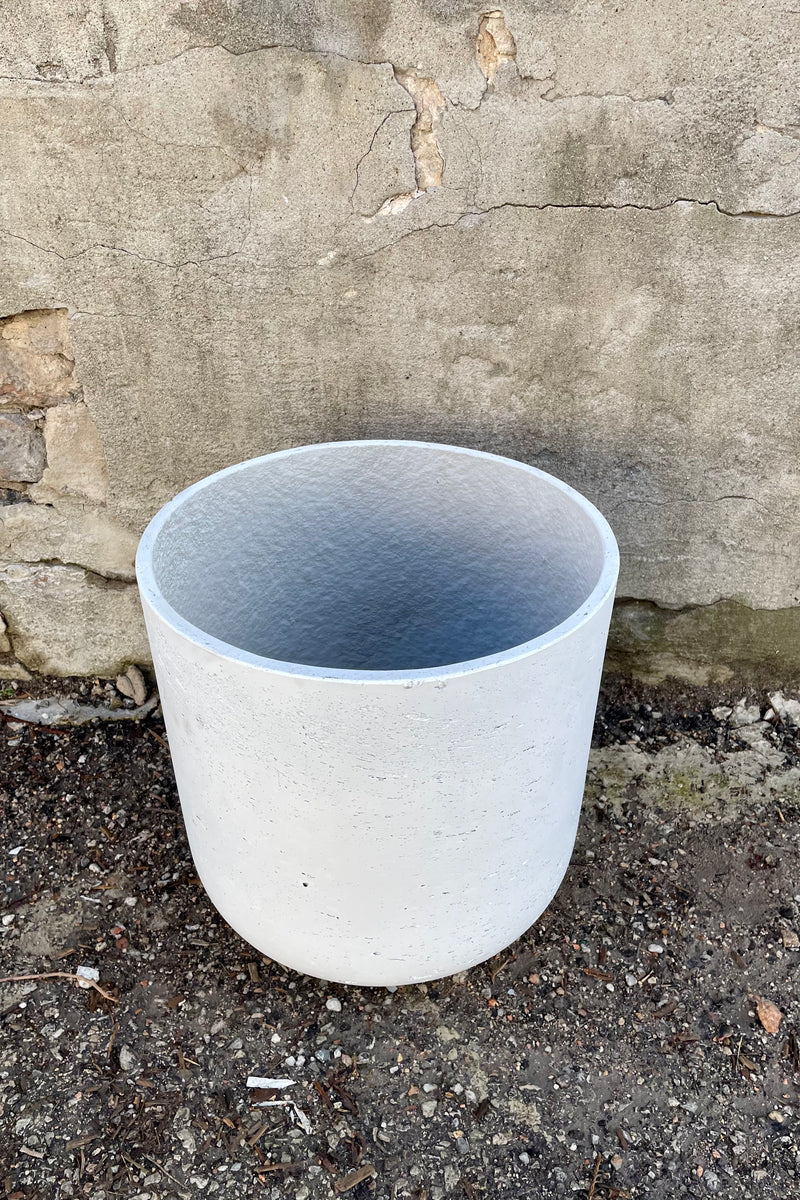 The Extra large white washed Charlie pot against a concrete wall and floor showing a little bit of the interior.