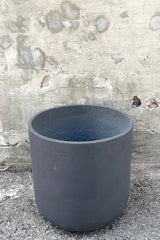 A slight over-the-lip view of the Charlie Pot black Washed Pot in extra extra large against a concrete backdrop