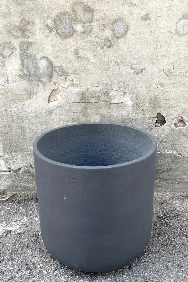 A slight over-the-lip view of the Charlie Pot black Washed Pot in extra extra large against a concrete backdrop