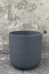 A frontal view of the Charlie Pot black Washed Pot in extra extra large against a concrete backdrop