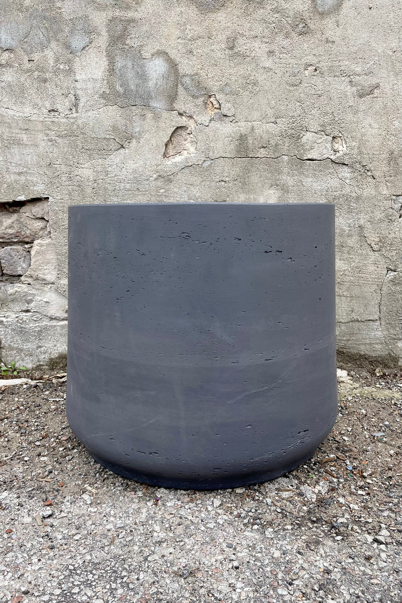 Patt Pot Black Washed Extra Extra Extra Large against a grey wall
