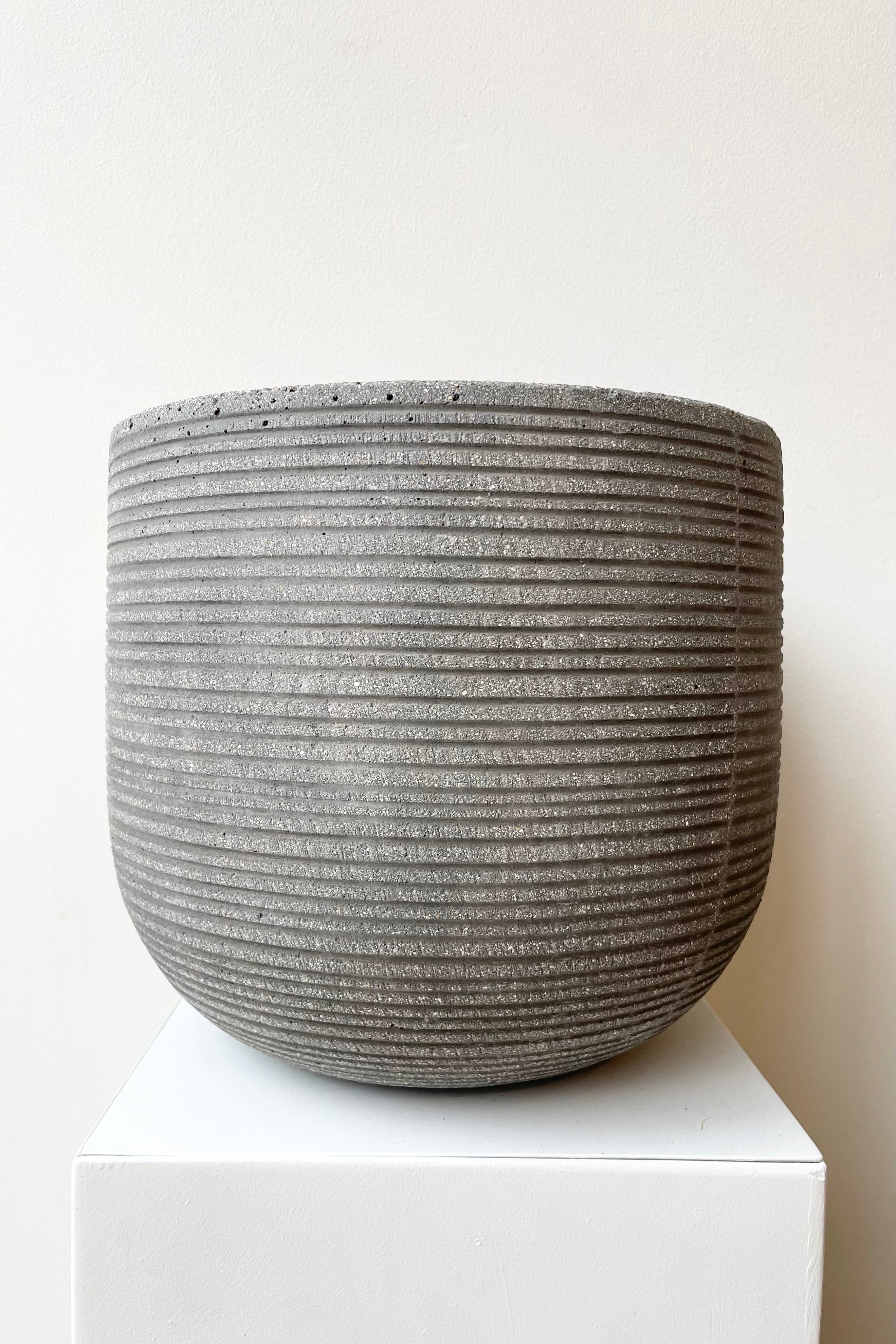 Cody Pot horizontal ridged dark grey small against a white wall