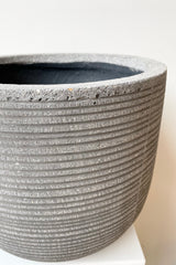 detail of Cody Pot horizontal ridged dark grey small against a white wall