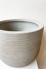 Detail of Cody Pot horizontal ridged light grey small against a white wall