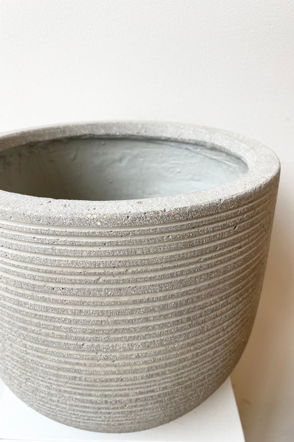 Detail of Cody Pot horizontal ridged light grey small against a white wall